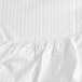 A close-up of a Garnier-Thiebaut white king size fitted sheet with a ruffled edge.