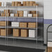 A wire shelving unit with four shelves holding boxes.