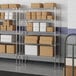 A white rectangular metal wire shelving unit with boxes on the shelves.