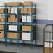 Lavex Pro blue metal wire shelving with white rectangular objects on shelves.