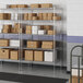 A metal wire shelf unit in a warehouse with boxes on the shelves.