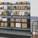 A blue Lavex Pro wire shelving unit with boxes on the shelves.