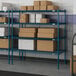 Blue metal Lavex Pro wire shelving in a warehouse with boxes on the shelves.