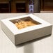 A white bakery box with a clear plastic window on a counter.