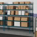 Blue metal Lavex Pro wire shelving unit in a warehouse with boxes.