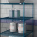 A Lavex Pro blue epoxy metal wire shelf with containers and buckets.