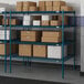 A blue Lavex Pro wire shelving unit with brown boxes on the shelves.