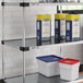 A Regency galvanized steel shelf with white and blue plastic containers on it.