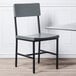 A BFM Seating Memphis side chair with a gray wooden seat and back on a table