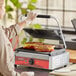 A woman cooking sandwiches on an Avantco commercial panini grill.