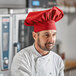 A man wearing a red Intedge chef hat in a professional kitchen.