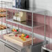 A stainless steel Avantco double deck overshelf over a counter with food on it.