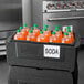 A black container with a Metro Mightylite BigBoy Food Pan inside filled with bottles of orange liquid.