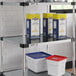 A Regency galvanized steel shelf with white and red plastic containers on it.