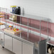 A stainless steel Avantco double deck overshelf on a counter in a commercial kitchen.