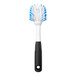 An OXO Good Grips dish brush with a blue and white handle and black and white bristles.