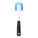 An OXO Good Grips dish brush with a white handle and blue and white bristles.