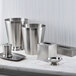 A Focus Hospitality Pewter Veil Collection stainless steel wastebasket on a white counter.
