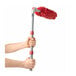 A long-handled dusting tool with a red microfiber head being held by two hands.