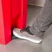 A person's foot stepping into a Rubbermaid red rectangular step-on trash can.