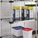 A Regency galvanized steel shelf with white and red containers with red lids on it.