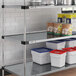 A Regency galvanized steel shelf with white and blue containers and a can of mushrooms on it.