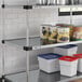 A Regency galvanized steel shelf in a kitchen with white and blue containers on it.