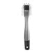 An OXO SteeL stainless steel dish brush with a black and silver handle.