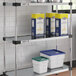 A Regency galvanized steel shelf with white and blue plastic containers on it.