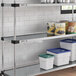 A Regency galvanized steel shelf with white and blue plastic containers on it.