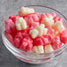 A white bowl filled with pink and white Albanese Lovestruck Gummi Bears.