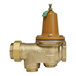 A close-up of a Watts brass water pressure reducing valve with a green valve.