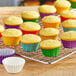 A rack of cupcakes with assorted rainbow cupcake liners.