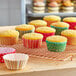 A group of cupcakes in Dots and Stripes cupcake wrappers on a cooling rack.