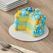 A Wilton white corrugated cake circle with a cake on top on a table.
