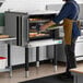 A single deck standard depth full size electric convection oven being used in a commercial kitchen.