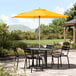 A Lancaster Table & Seating yellow umbrella on a round outdoor table.