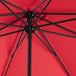 A close up of a red Lancaster Table & Seating umbrella with black poles.