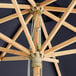 A Lancaster Table & Seating indigo blue bamboo umbrella with a pulley lift.