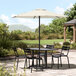 A table and chairs on a patio with a Lancaster Table & Seating Ivory Umbrella over the table.