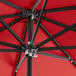 A close up of a red Lancaster Table & Seating umbrella with black metal poles.