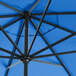 A close up of a cobalt blue Lancaster Table & Seating umbrella with black poles.