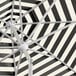 A close up of a Lancaster Table & Seating black and white striped umbrella with a silver pole.