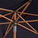 A close up of a Lancaster Table & Seating navy umbrella with a woodgrain pole.