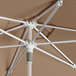 A close-up of a Lancaster Table & Seating silver aluminum umbrella with a wheat-colored canopy.