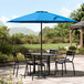 A Lancaster Table & Seating blue umbrella on an outdoor patio table.