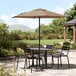 A Lancaster Table and Chairs under a black umbrella on a patio.