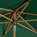 A Lancaster Table & Seating forest green umbrella with woodgrain poles.