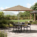 A Lancaster Table & Seating silver aluminum umbrella over a table and chairs on a concrete patio.