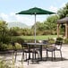 A forest green umbrella on a table with chairs on an outdoor patio.